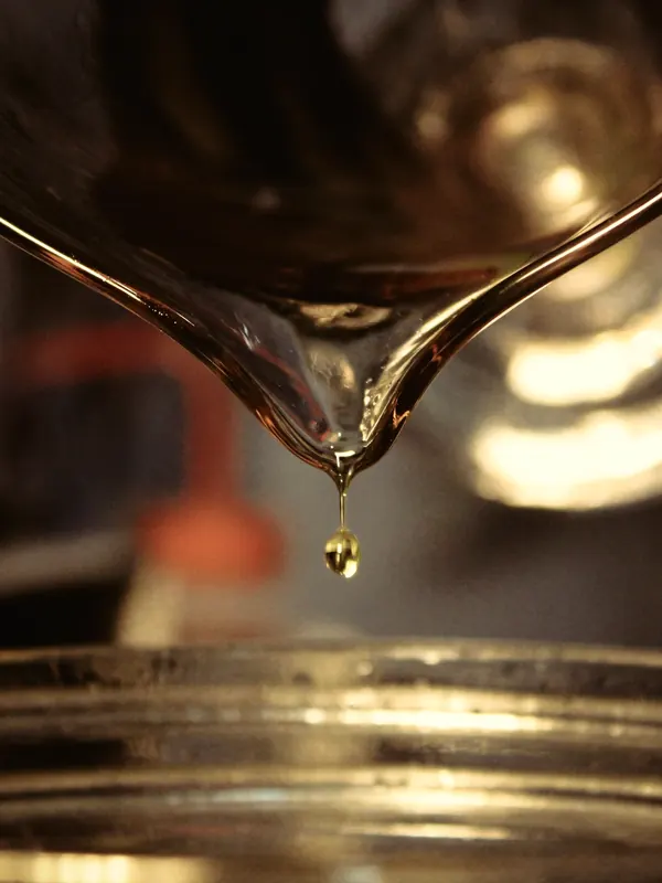 A single drop of clear broth falling into a glass