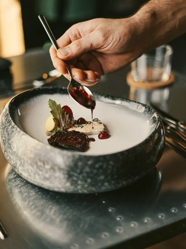 Sauce spooned over venison in a stone bowl