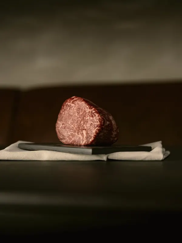 A block of deeply marbled beef on a dark counter