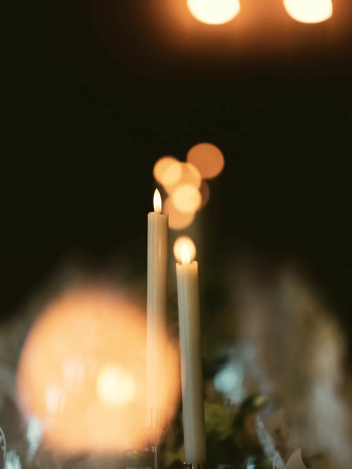 Candle flames softly out of focus in a dark room