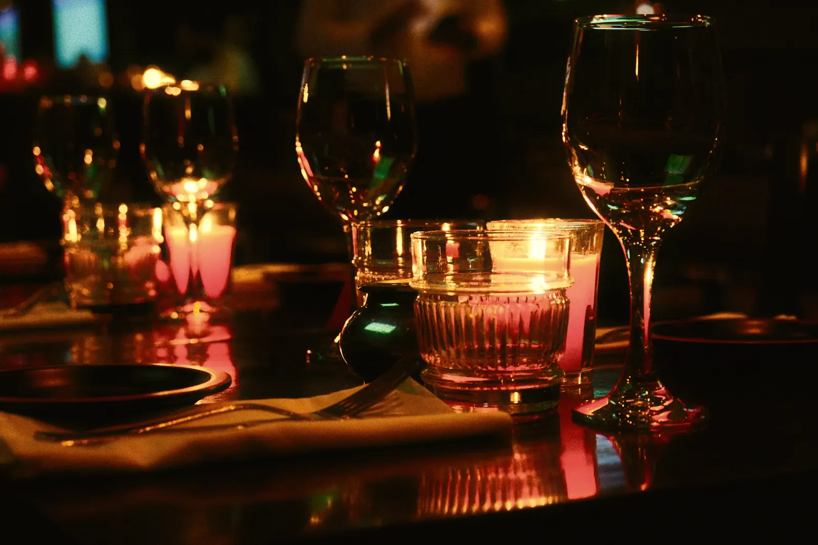 Candles and wine glasses on a dimly lit table