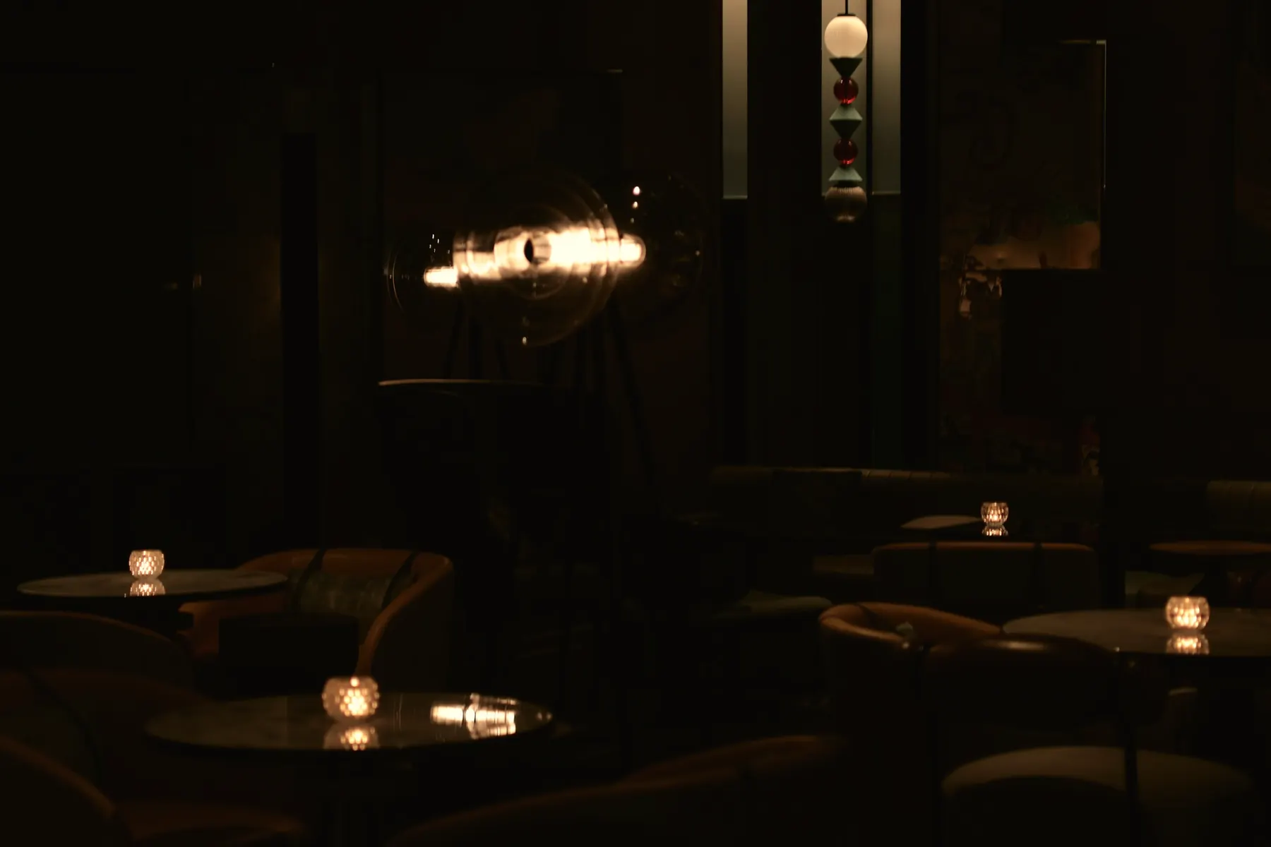 A dim, candlelit room with low lamps and dark wood